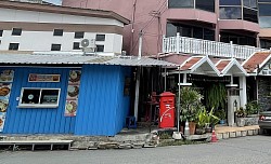 It is marked by a red post box. There is a blue building next door